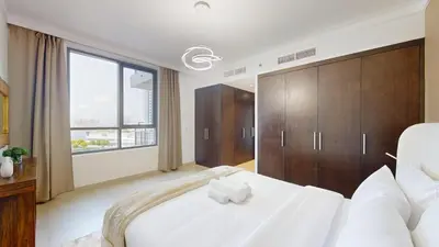 a bedroom with a white bed and a large window at Creek Residences - Opulent Two Bed with Creek View in Dubai