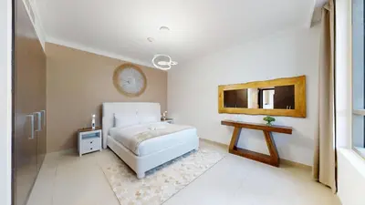 a bedroom with a white bed and a table at Creek Residences - Opulent Two Bed with Creek View in Dubai