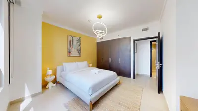 a bedroom with a white bed and a yellow wall at Creek Residences - Opulent Two Bed with Creek View in Dubai