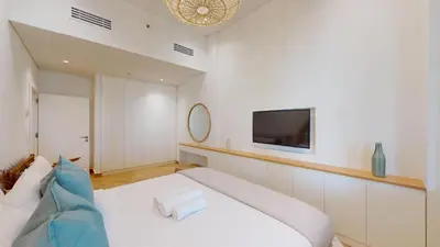 a bedroom with a white bed and a tv on the wall at Al Dabas 2 - Calm One Bedroom in Palm Jumeirah in Dubai