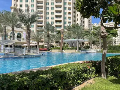 a swimming pool with palm trees and a large building at Al Dabas 2 - Calm One Bedroom in Palm Jumeirah in Dubai
