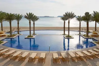 a pool with chairs and palm trees and the beach at Al Dabas 2 - Calm One Bedroom in Palm Jumeirah in Dubai