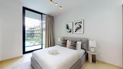 a white bedroom with a bed and a large window at Binghatti Crescent - Two Bed with Pool View in JVC in Dubai