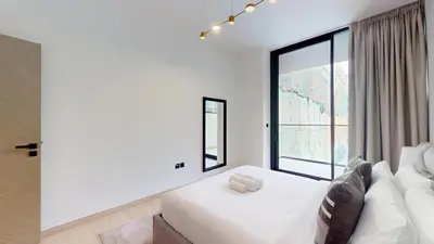 a bedroom with a white bed and a large window at Binghatti Crescent - Two Bed with Pool View in JVC in Dubai