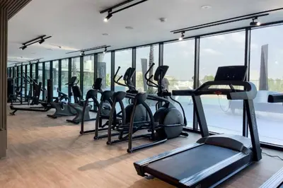 a gym with a lot of treadmills and a lot of windows at Binghatti Crescent - Two Bed with Pool View in JVC in Dubai