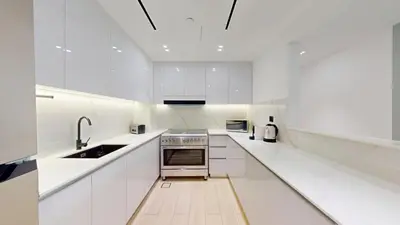 a white kitchen with a sink and a stove at Binghatti Crescent - Two Bed with Pool View in JVC in Dubai