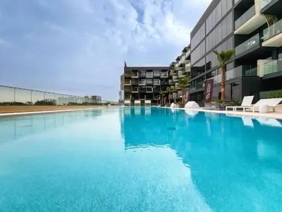 a large blue swimming pool in front of a building at Binghatti Crescent - Two Bed with Pool View in JVC in Dubai