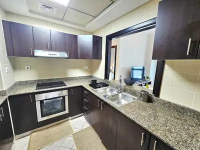 a kitchen with wooden cabinets and a sink in it at Amazing 1BR High-floor with Breathtaking View near Marina Walk in Dubai