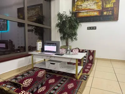 a desk with a laptop on a table on a rug at Happyland JBR Dubai Hostel in Dubai