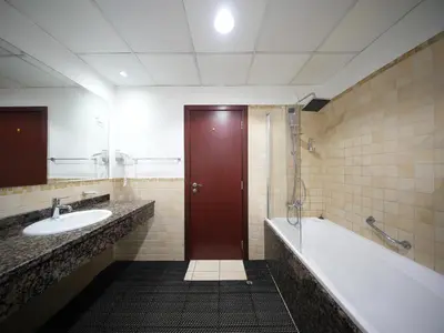 a bathroom with a tub and a sink and a red door at Happyland JBR Dubai Hostel in Dubai