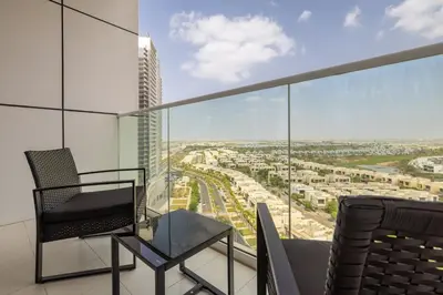 a chair and a table on a balcony with a view at Maison Privee - Stylish Studio with Top Facilities in Damac Hills in Dubai