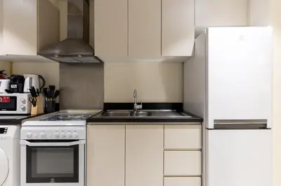 a kitchen with white cabinets and a sink at Maison Privee - Stylish Studio with Top Facilities in Damac Hills in Dubai