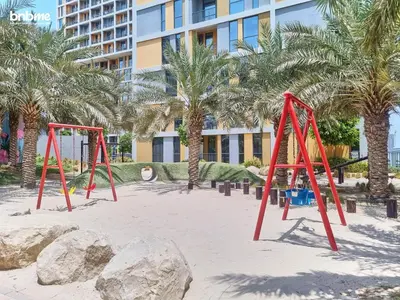 a playground with red swings in front of a building at bnbmehomes - Afnan 4 - Midtown in Dubai
