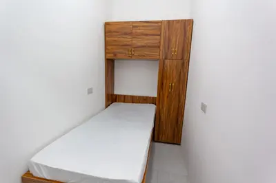a small bedroom with a bed and wooden cabinets at Rental Small Rooms for female guest in the heart of Dubai بنات فقط in Dubai