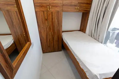 a small room with two beds and wooden cabinets at Rental Small Rooms for female guest in the heart of Dubai بنات فقط in Dubai