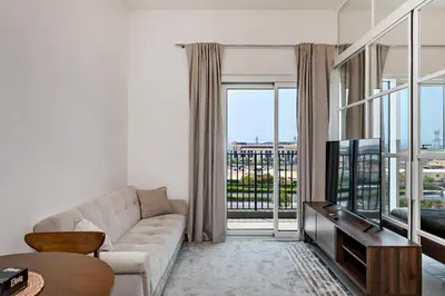 a living room with a couch and a tv at Dubai Hills Cozy 1Br Golfville in Dubai