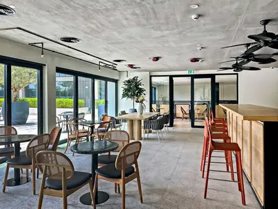 a restaurant with tables and chairs and windows at Dubai Hills Cozy 1Br Golfville in Dubai