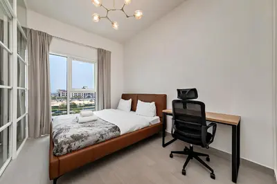 a bedroom with a bed and a desk and a chair at Dubai Hills Cozy 1Br Golfville in Dubai