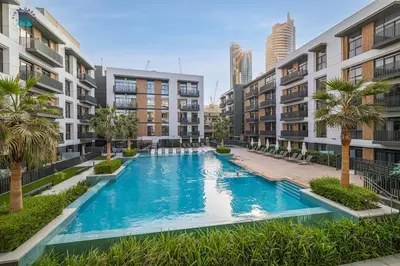 an apartment pool with palm trees and buildings at Contemporary 2-BR at Belgravia Square JVC in Dubai