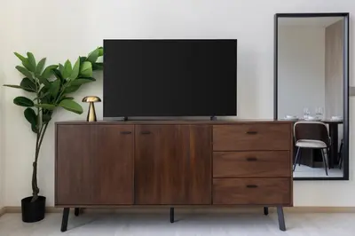 a television on top of a wooden dresser in a living room at Stylish Duplex Autograph 1BR in Dubai