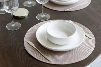 a wooden table with white plates and forks and wine glasses at Stylish Duplex Autograph 1BR in Dubai