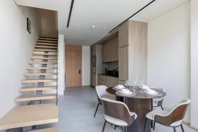 a dining room with a table and chairs and a staircase at Stylish Duplex Autograph 1BR in Dubai