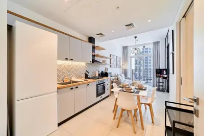 a kitchen with white cabinets and a table with chairs at Chic & Modern 1BR in Socio Near Dubai Hills Park in Dubai
