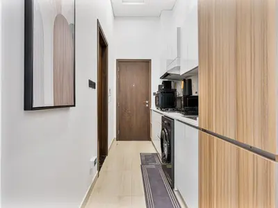a kitchen with a washer and dryer next to a door at Savis Homes - Luxury Brand New Studio in Elysee III in JVC in Dubai