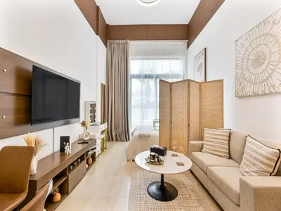 a living room with a couch and a tv at Savis Homes - Luxury Brand New Studio in Elysee III in JVC in Dubai