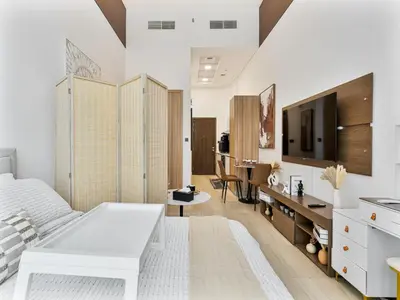 a bedroom with a white bed and a desk at Savis Homes - Luxury Brand New Studio in Elysee III in JVC in Dubai