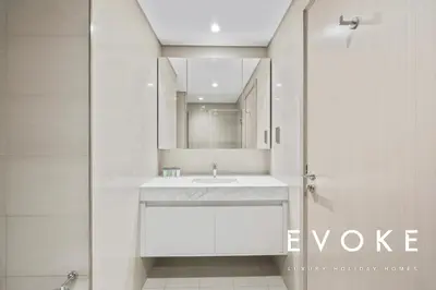a white bathroom with a sink and a mirror at Full Burj & Fountain View - Evoke 2BR at Burj Royale in Dubai