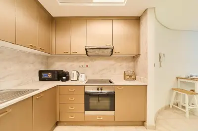 a kitchen with brown cabinets and a stove top oven at 1BR Sky Gardens Balcony with Stunning DIFC View in Dubai