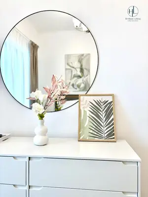 a mirror over a white table with a vase with flowers at Downtown Living - Business Bay 1BR in Dubai