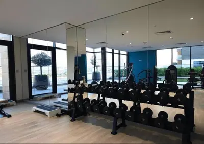 a gym with a large mirror and lots of equipment at Cosy studio in Dubai