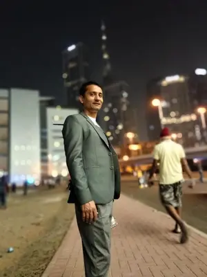 a man in a suit standing on a sidewalk at California Village Dubai in Dubai