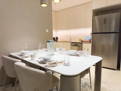 a kitchen with a white table with chairs and a refrigerator at ADDRESS BEACH RESORT Residence Million Dollar View 39th floor DXB AIRPORT VIP Shuttle option in Dubai