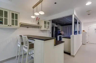 a kitchen with white cabinets and a bar with chairs at Shams, JBR - 2BR Apartment - Allsopp & Allsopp in Dubai