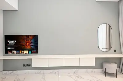 a living room with a tv on a wall at Modern Comfort with Pool and Free Parking Near Dubai Fountain and Burj Khalifa in Dubai