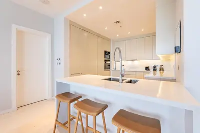 a kitchen with white cabinets and a counter with stools at Stunning Sea View 3BR with Private Beach in Dubai