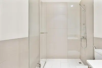 a white bathroom with a shower and a sink at Bright 1BR APT in Dubai Hills Near Burj Khalifa in Dubai