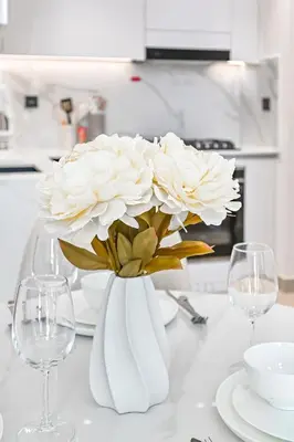 a white vase with white flowers on a table at Golden Stays - Binghatti Tulip I Chic 1BR Apartment I Balcony Views I JVC Dubai in Dubai