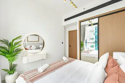 a white bedroom with a large bed and a mirror at Golden Stays - Binghatti Tulip I Chic 1BR Apartment I Balcony Views I JVC Dubai in Dubai