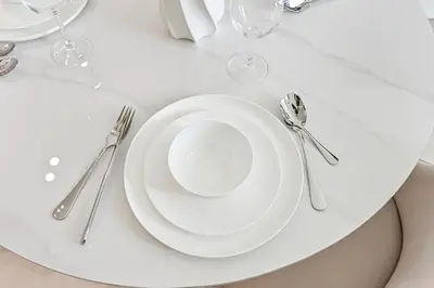 a white plate on a white table with silverware at Golden Stays - Binghatti Tulip I Chic 1BR Apartment I Balcony Views I JVC Dubai in Dubai
