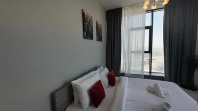 a bedroom with a white bed with red pillows and a window at High Floor 2 Bedroom in V Tower in Dubai