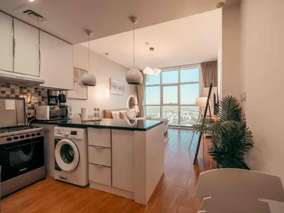 a kitchen with a washer and dryer in it at Cozy Studio Themed Designed In JVT in Dubai