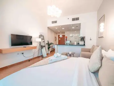 a room with a bed and a living room at Cozy Studio Themed Designed In JVT in Dubai