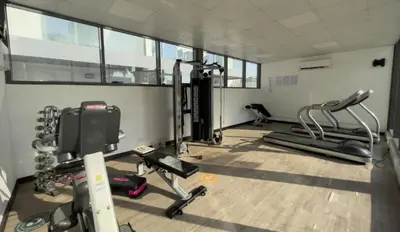 a gym with treadmills and machines in a room at Cozy Studio in JVC in Dubai