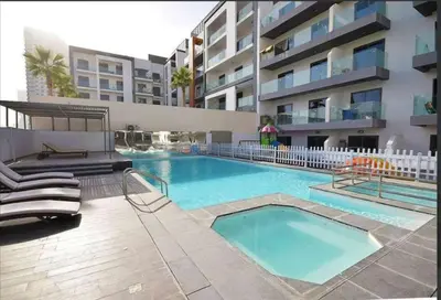 a swimming pool in front of a apartment building at Cozy Studio in JVC in Dubai
