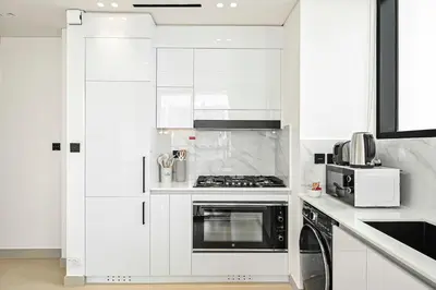 a white kitchen with a stove and a microwave at Golden Stays - Private Pool in Binghatti Tulip I Prime JVC 2BR I Balcony Access in Dubai