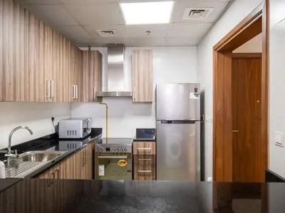 a kitchen with a stainless steel refrigerator and wooden cabinets at Elegant 1BR near from Dubai Mall & Burj Khalifa in Dubai